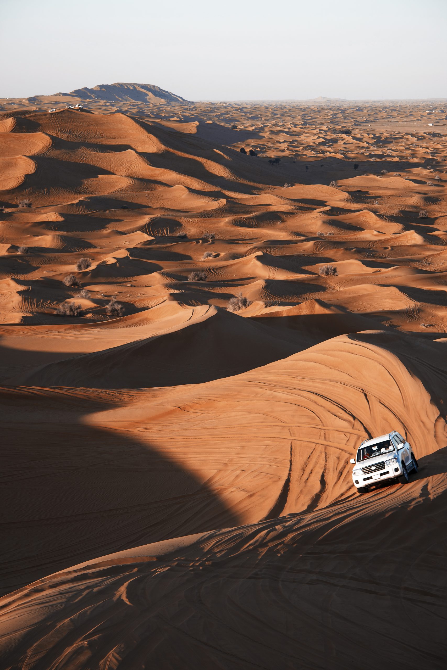 Safari on off-roader driving between sand dunes in sunny day in Dubai, United Arab Emirates