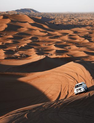 Safari on off-roader driving between sand dunes in sunny day in Dubai, United Arab Emirates